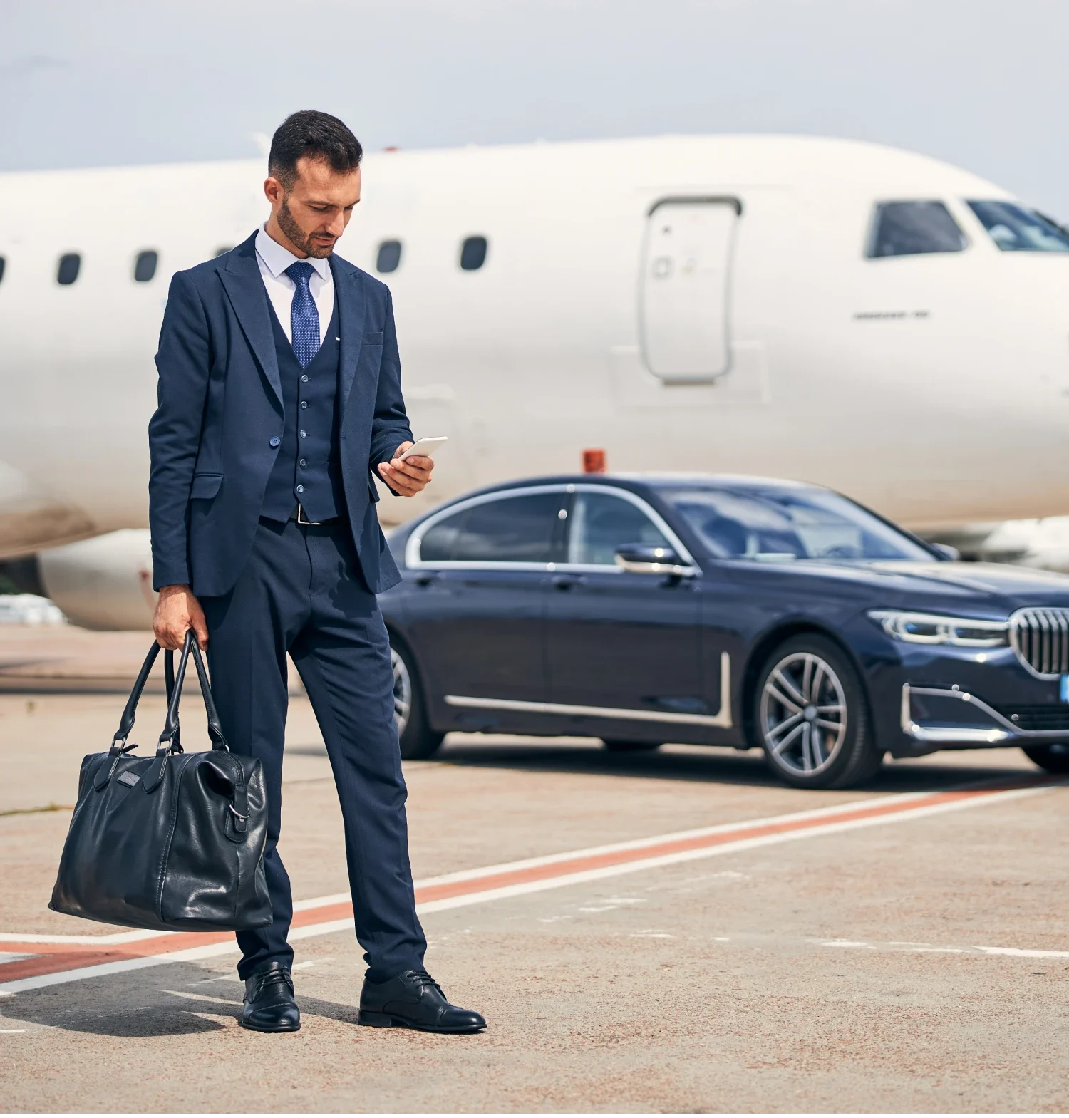 Businessman in suit stands by BMW 7 Series on airport tarmac, ready to travel.