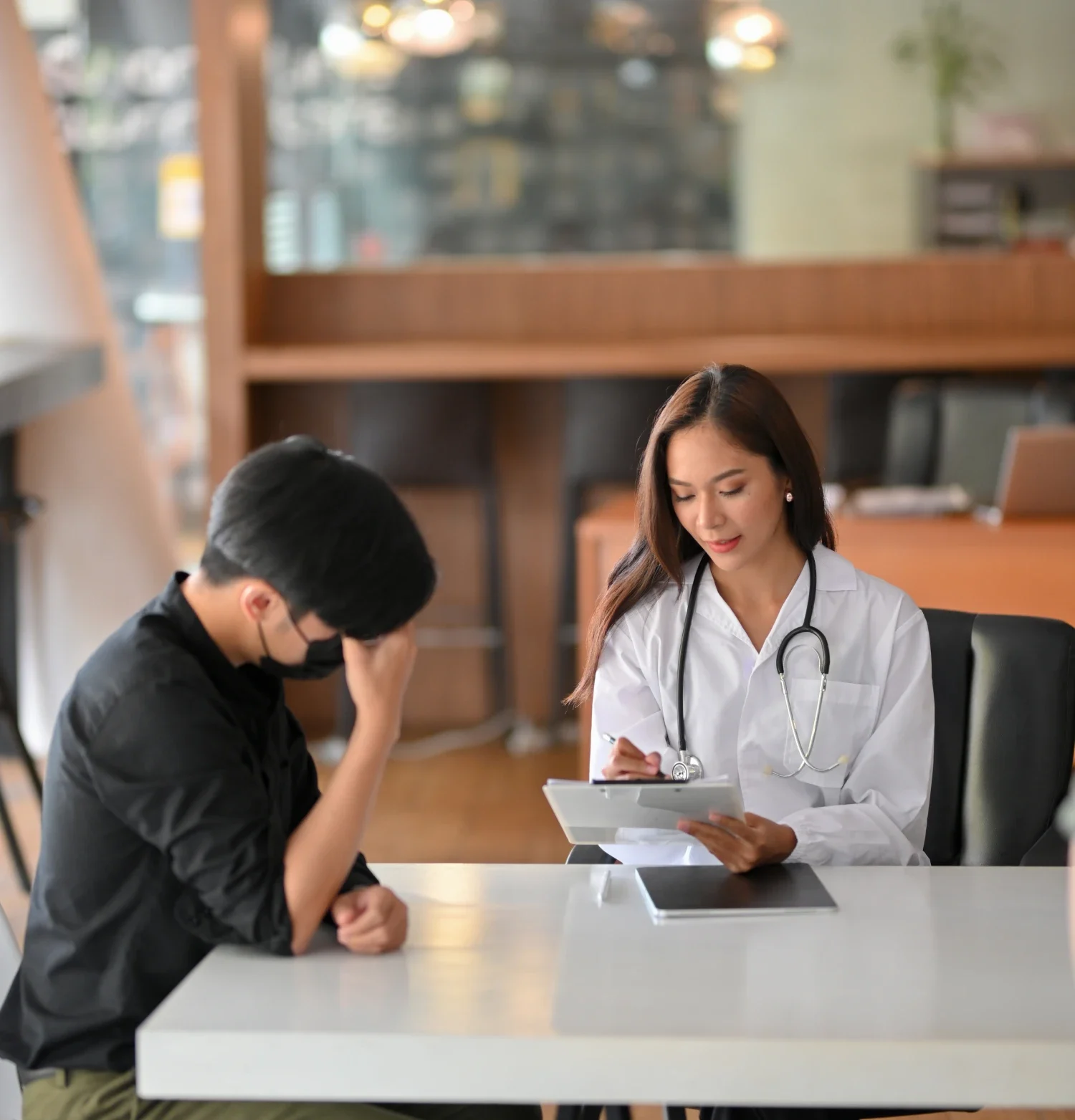 Asian doctor discussing health concerns with a patient in a clinical setting.