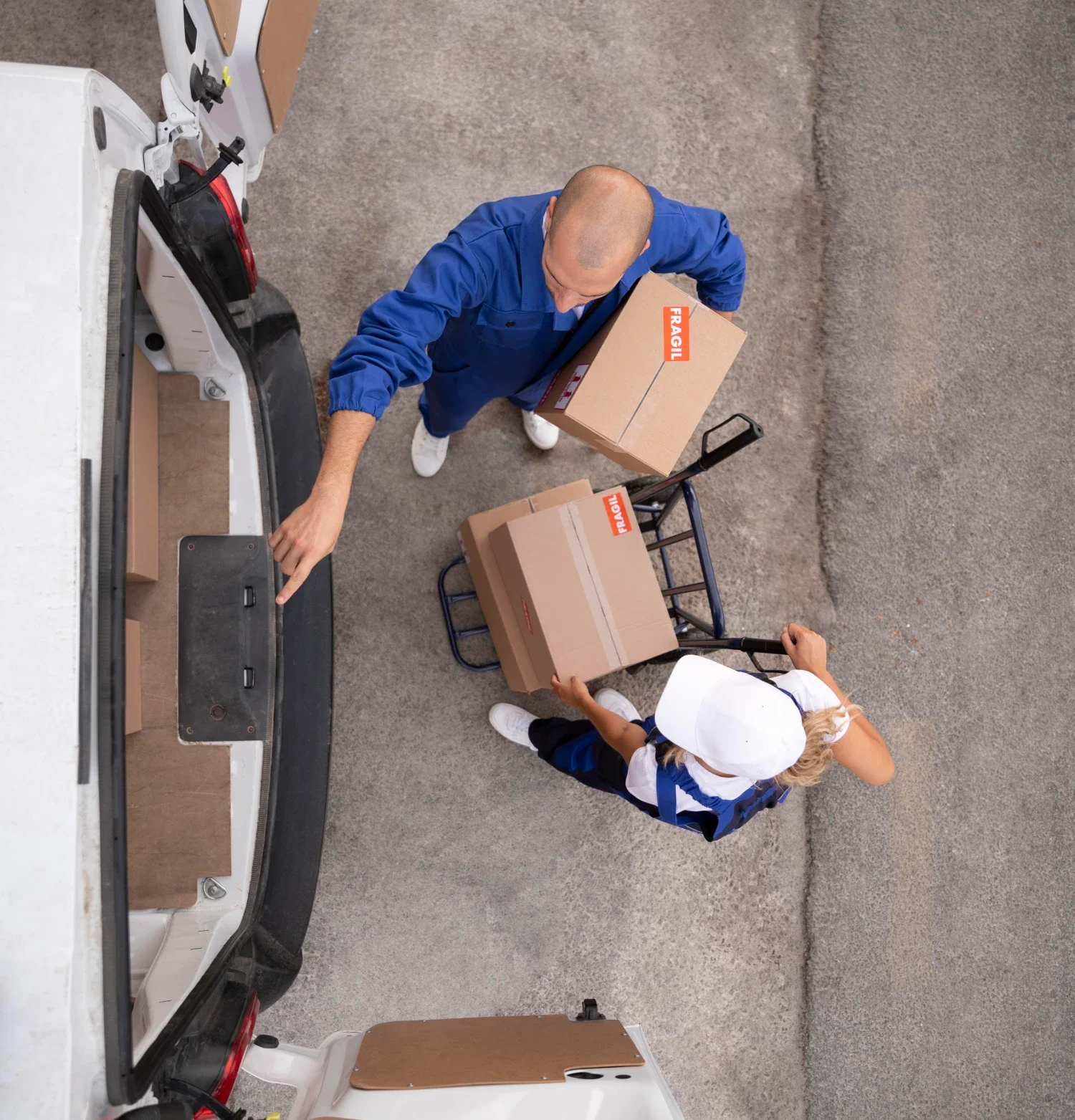Two individuals are loading cardboard boxes into the back of a moving truck.